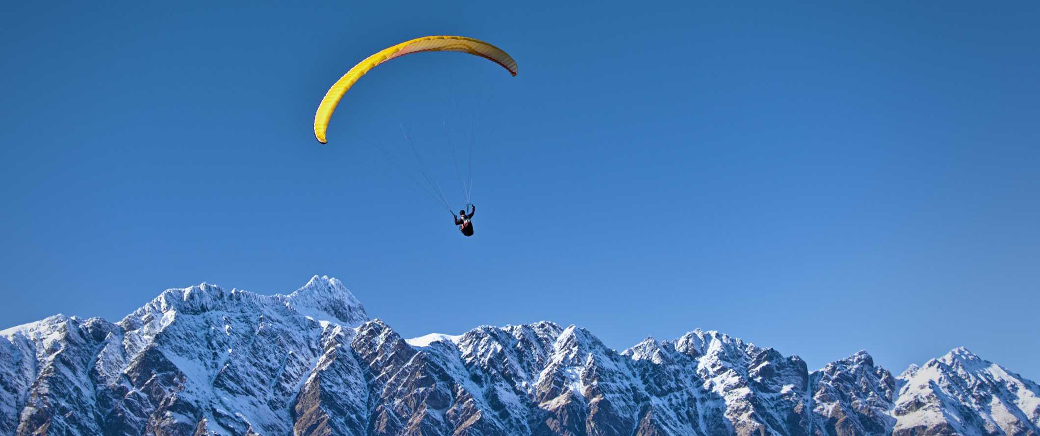 Someone parachuting over snowy mountaintops in New Zealand.