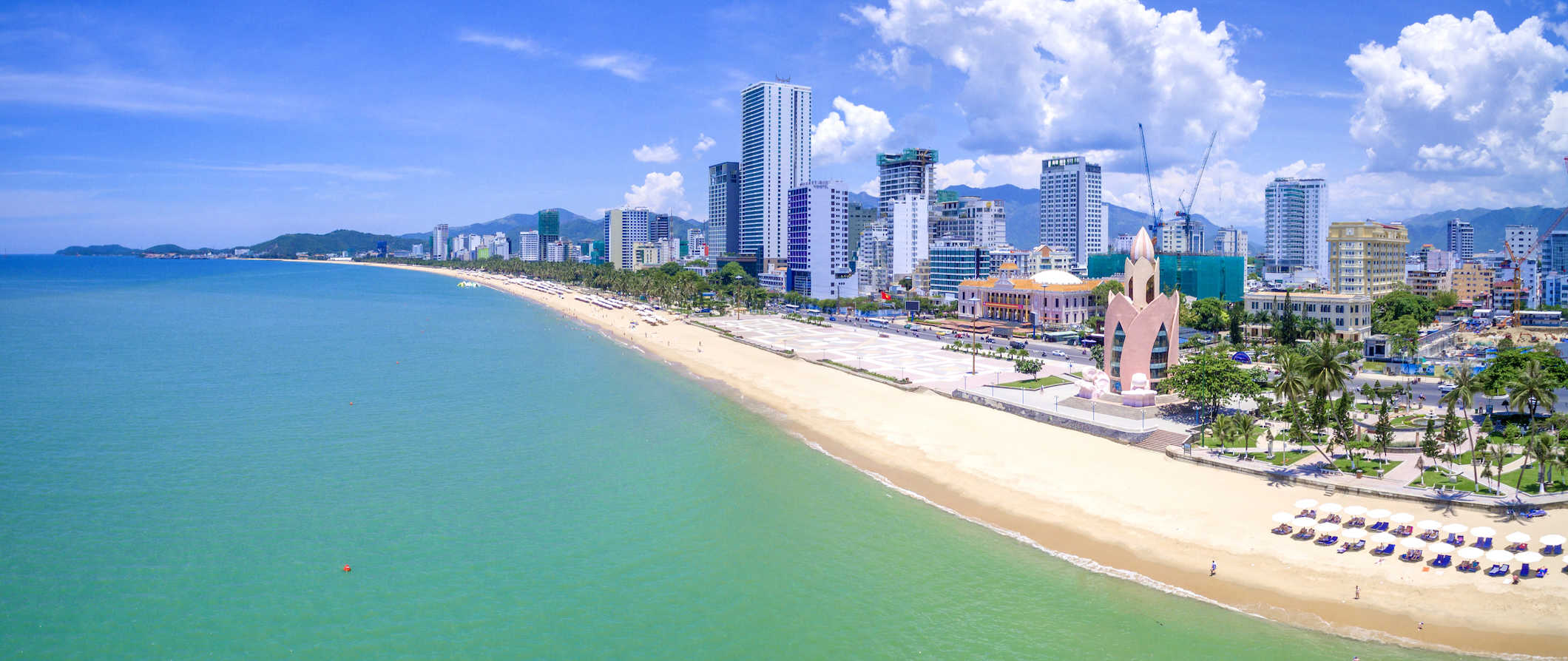 The beach scene along the coats of Nha Trang, Vietnam with the city skyline towering along the coastline