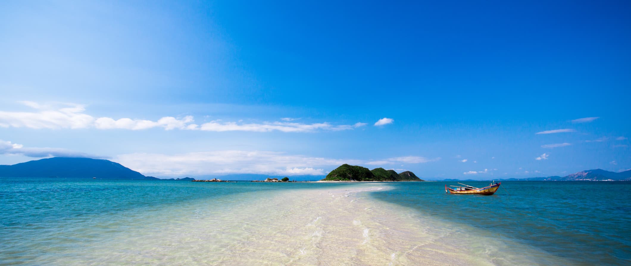 The relaxing beach along the coast of Nha Trang, Vietnam with a small boat floating near a sandbar