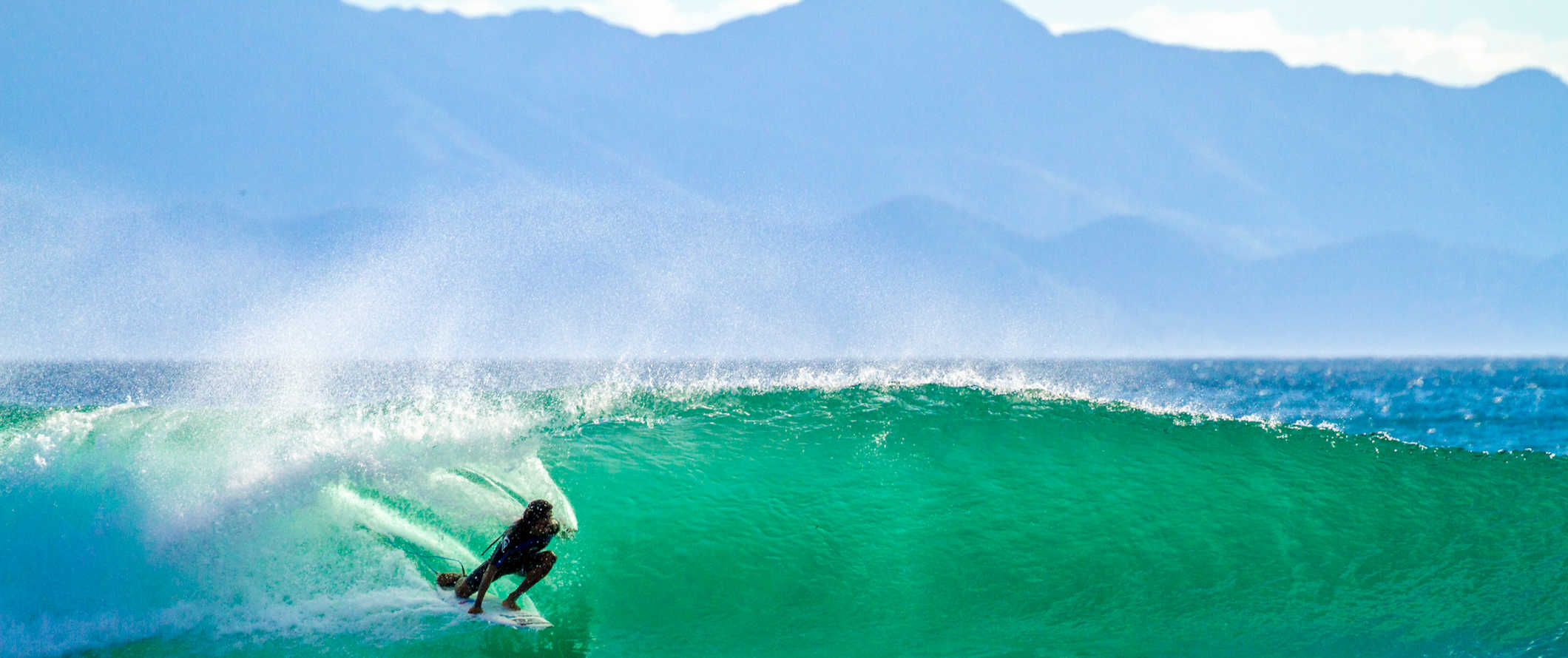 A woman surfing epic waves in the clear waters of Nicaragua