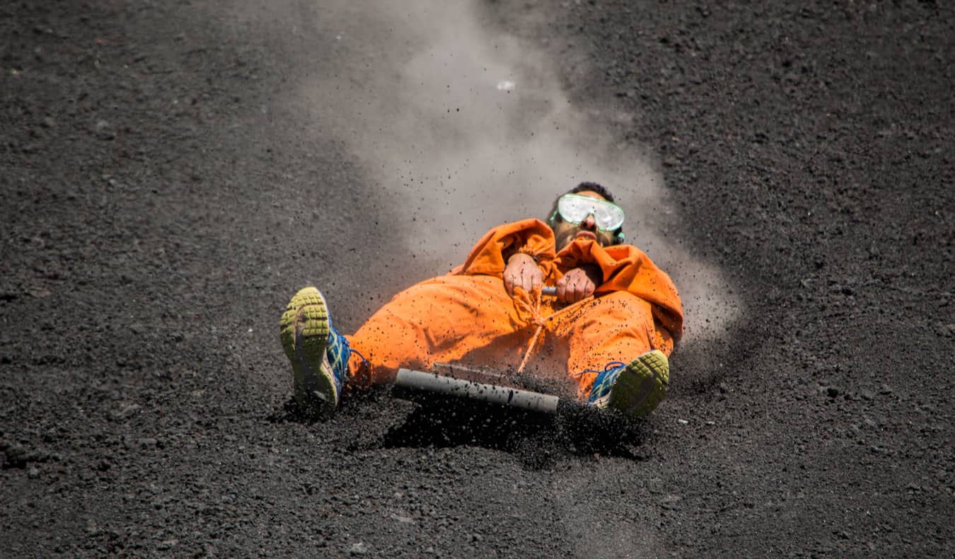 A backpacker volcano boarding down the slope of Cerro Negro in Nicaragua
