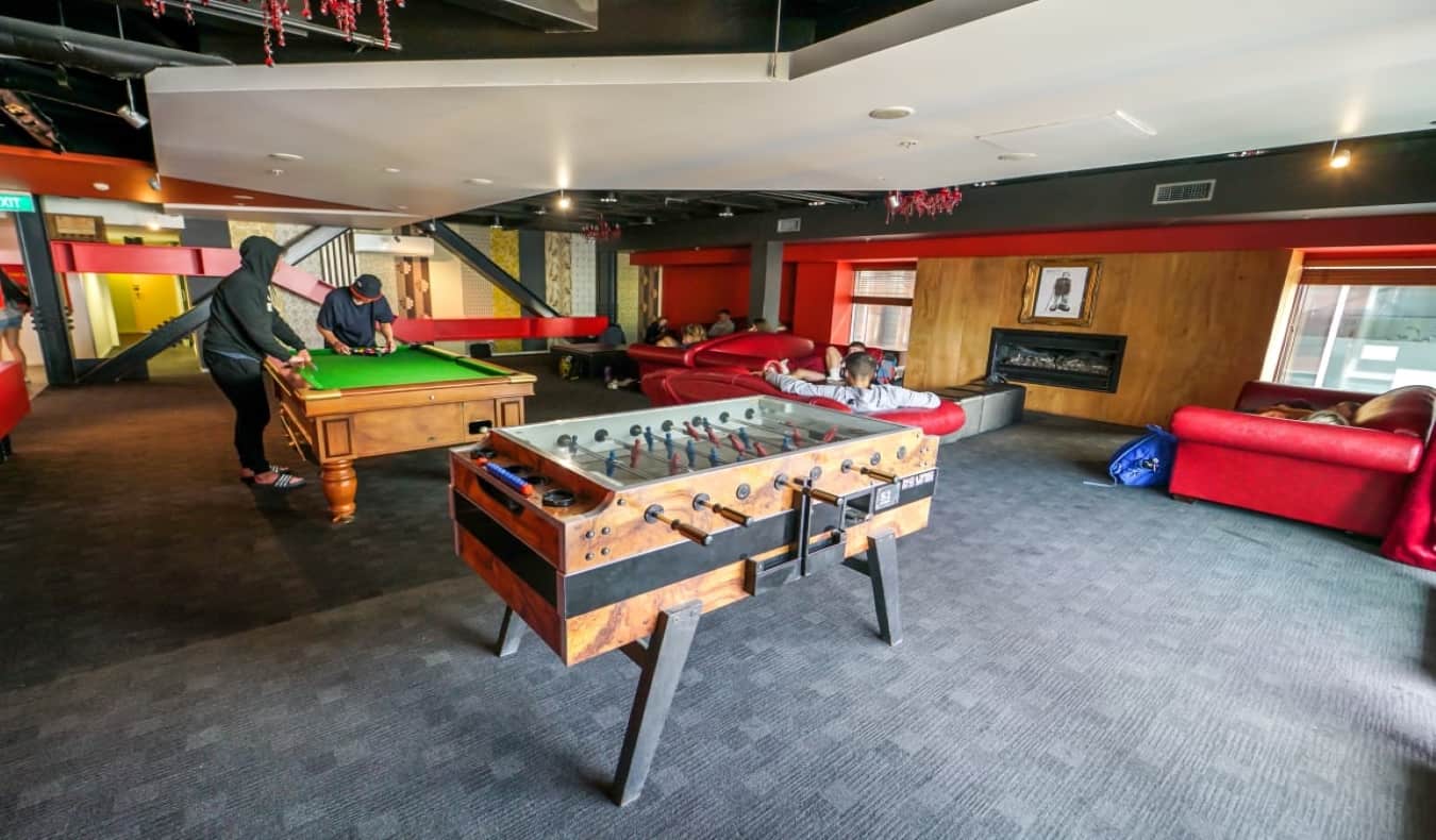 lounge with pool and foosball table at nomad's hostel in queenstown new zealand