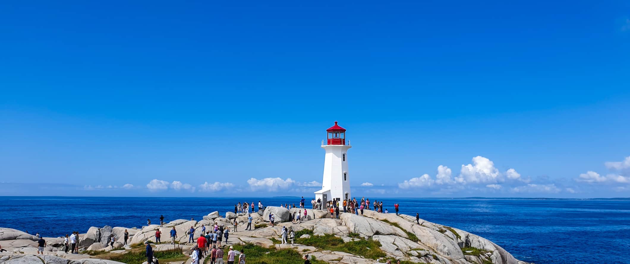 The iconic white lighthouse in Peggy's Cove, Nova Scotia on a sunny summer day