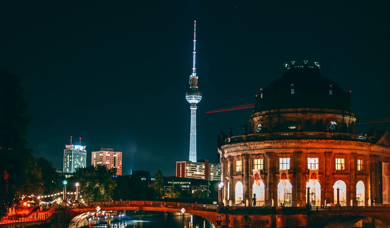 Downtown Berlin lit up at night, with the city's iconic tower standing tall in the distance