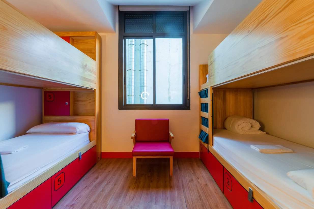 Dorm room with 2 wooden bunk beds with red storage drawers underneath at Ok Hostel in Madrid, Spain.