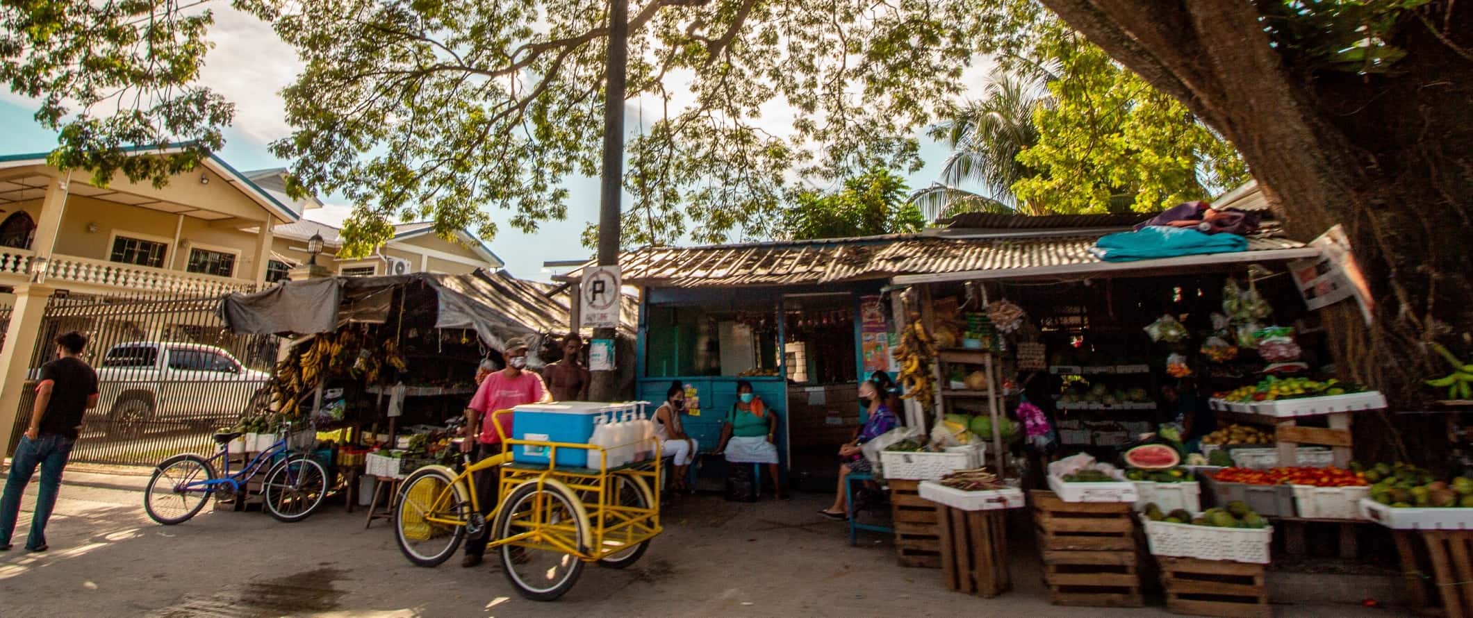 Street scene with people gathered at produce stands in Orange Walk, Belize