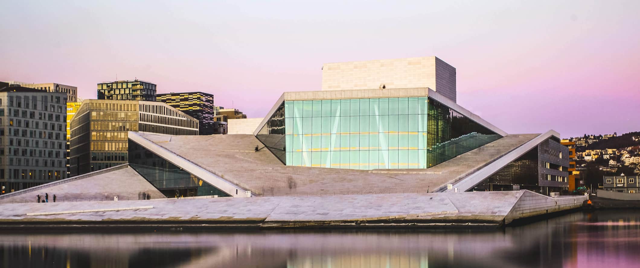 The iconic opera building on the shore of Oslo, Norway during a colorful sunset
