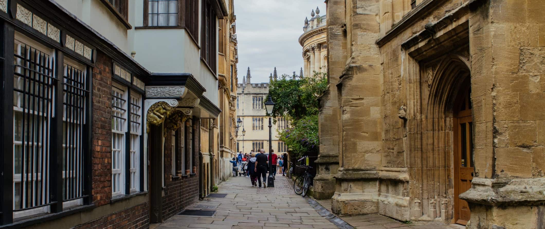 People walking down one of the historic, flagstone-lined lanes at the University of Oxford in the town of Oxford, England