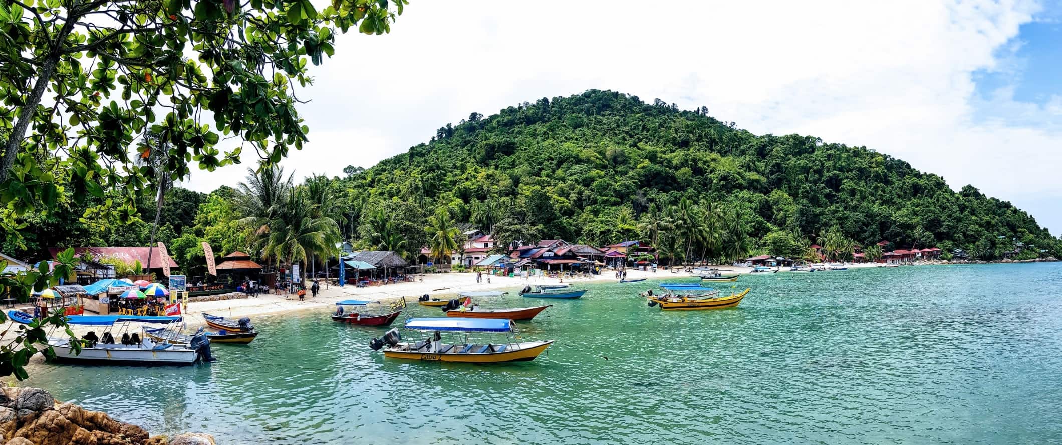 Boats anchored in the water off a beach in the Perhentian Islands, Malaysia