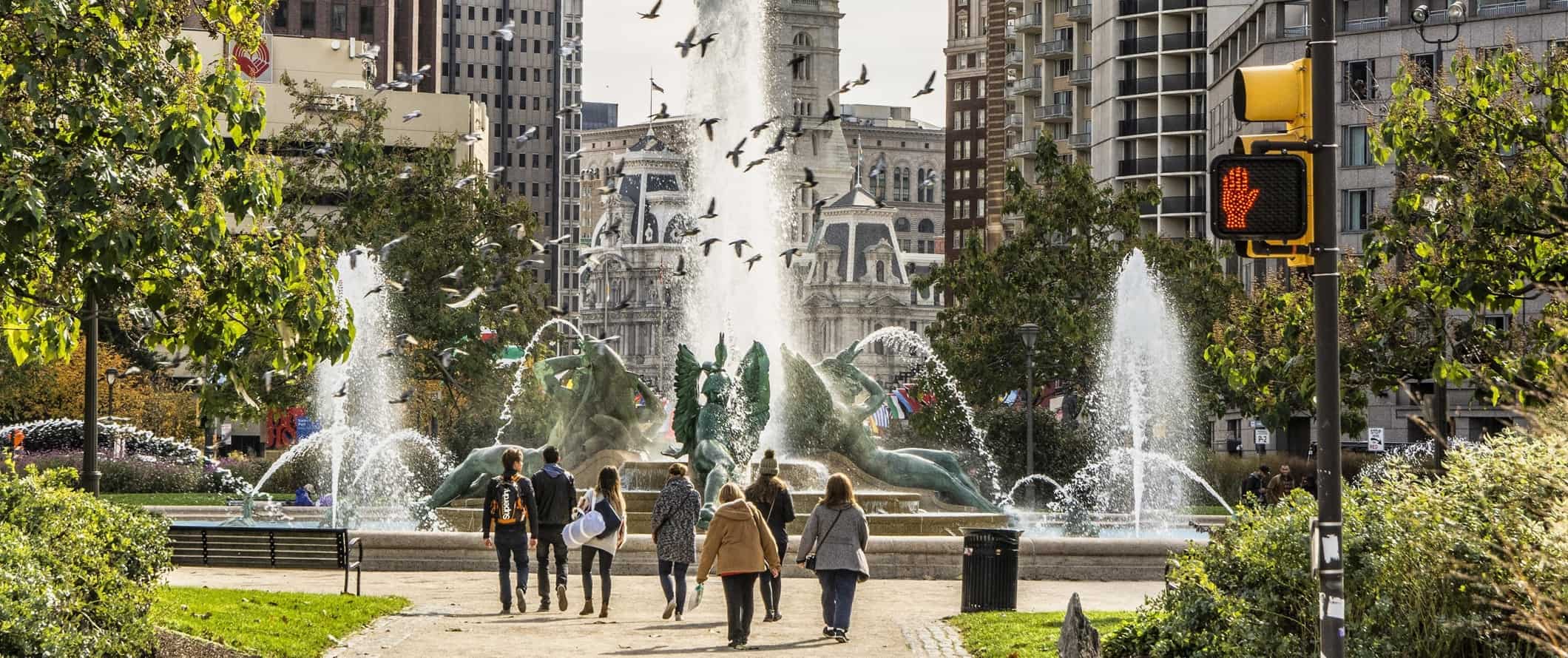 People walking in an urban park in front of a fountain in Philadelphia, USA