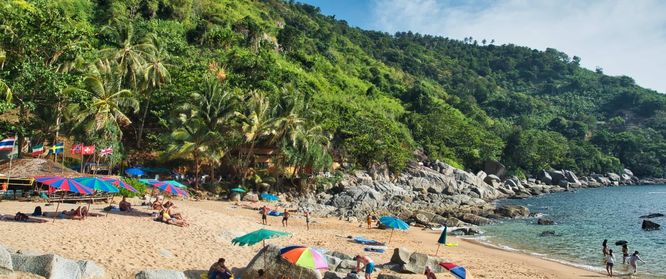 People lounging on a sandy beach in Phuket, Thailand