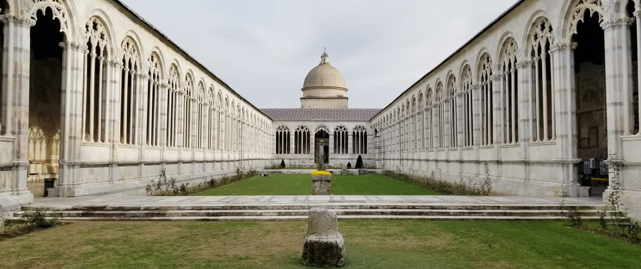 Cloistered quadrangle with dome in the background in Pisa, italy