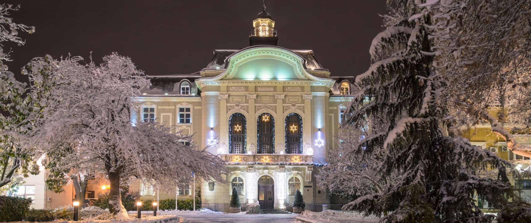 A large historic building surrounded by snow-covered trees in the Old Town of Plovdiv, Bulgaria