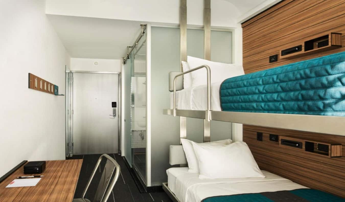 Modern bunk beds, desk, and door leading to en-suite bathroom at Pod Hotel Times Square