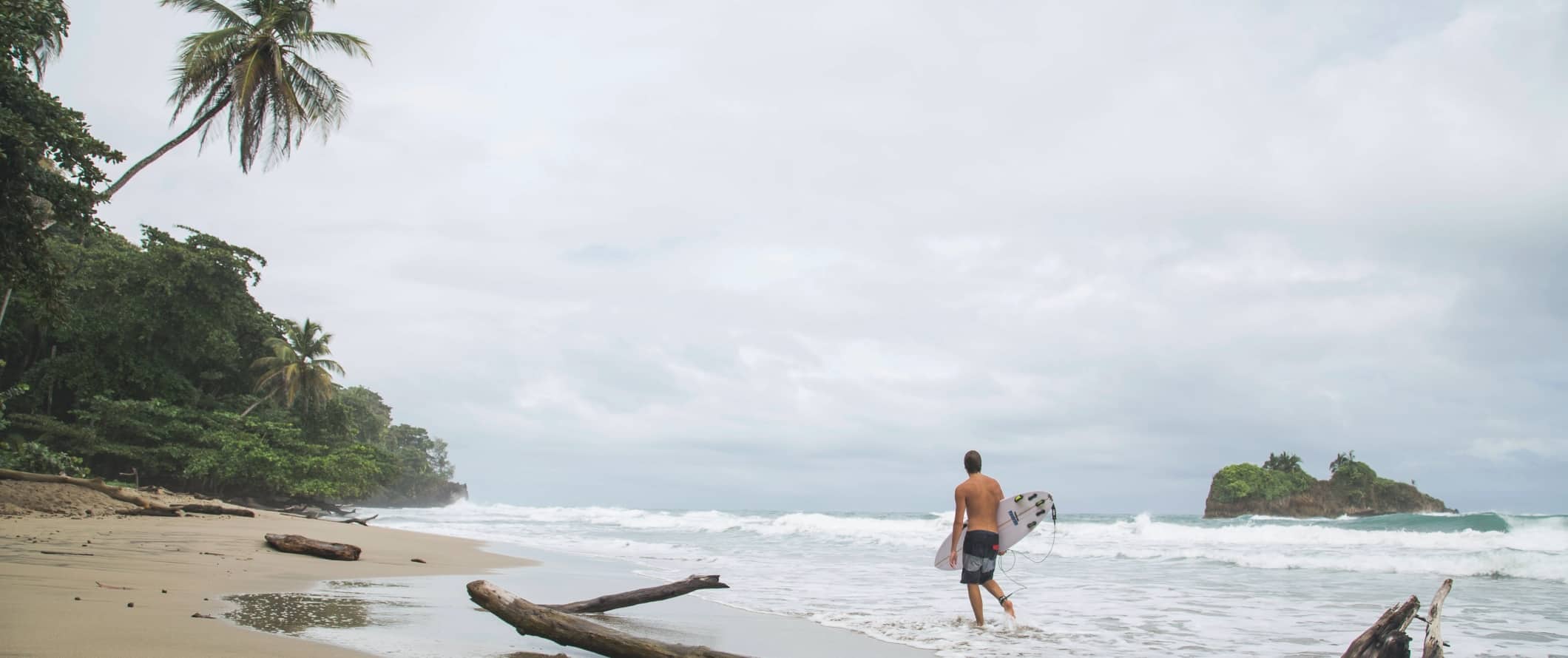 Person walking down the beach with a surfboard in Puerto Viejo, Costa Rica