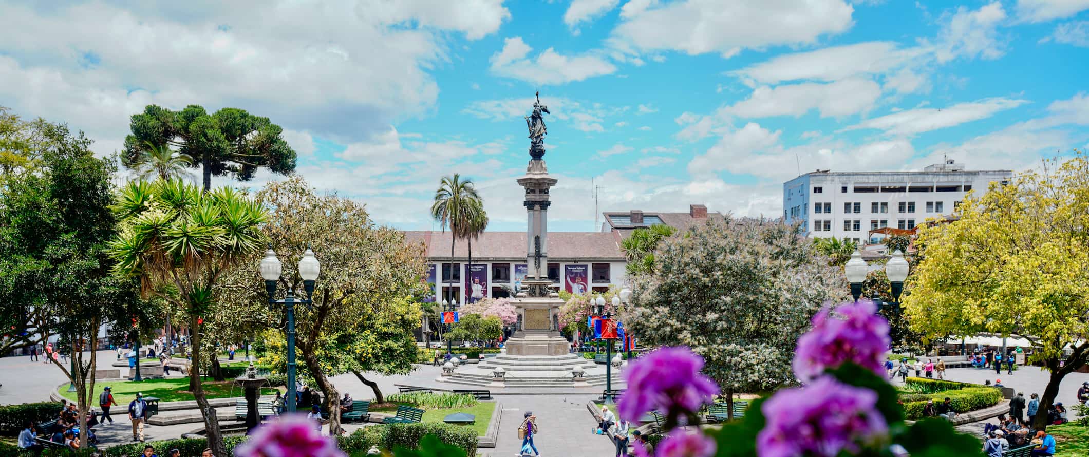 Colorful flowers near a square with a statue and fountain in sunny Quito, Ecuador