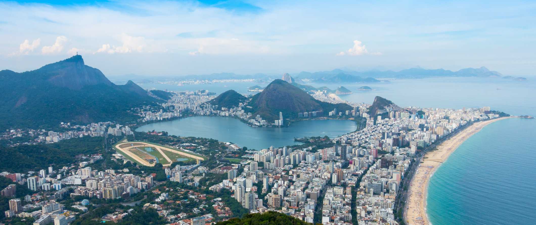 Panoramic view of Rio de Janeiro with skyscrapers along the beach and mountains in the background