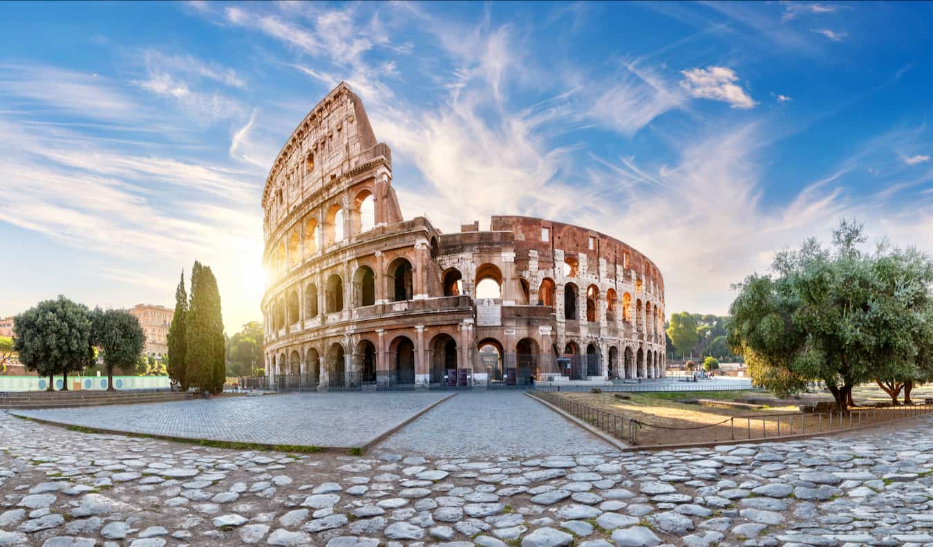 The massive colosseum in Rome, Italy with the bright sun in the background on a sunny day