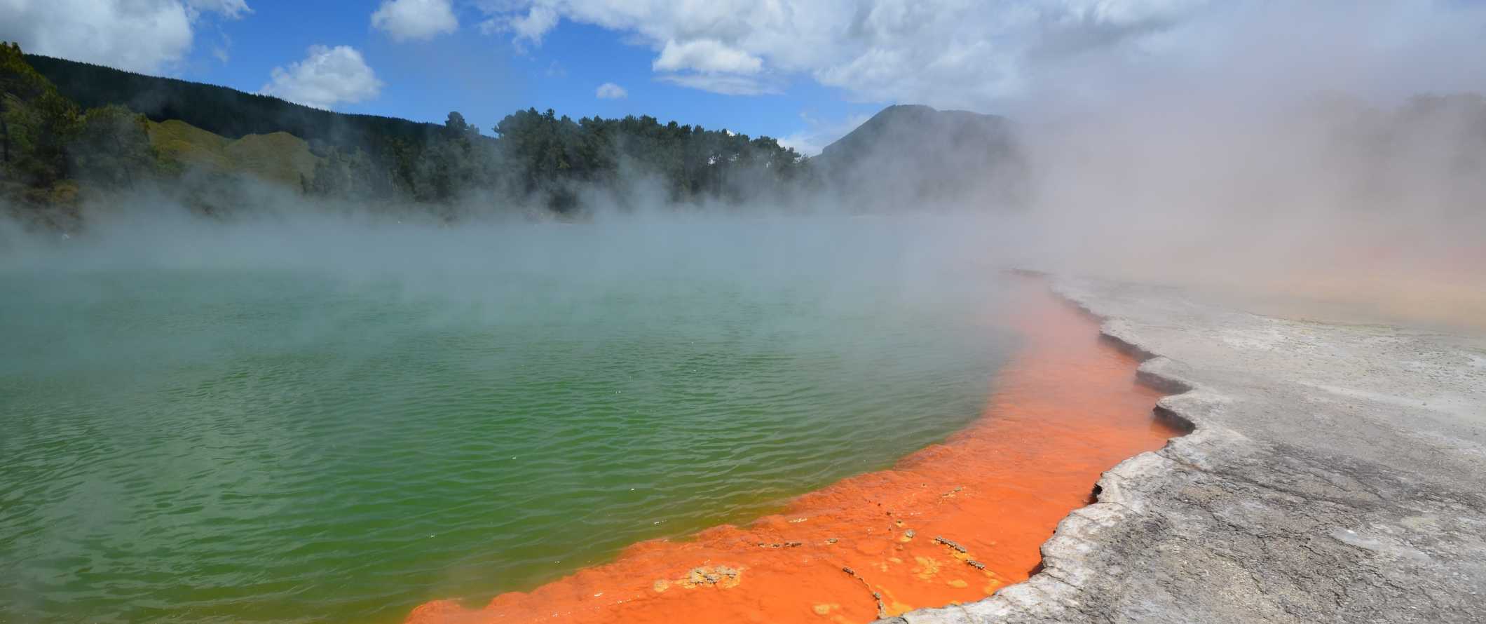 Cloudy turquoise hot springs with steam rising from them in Rotorua, New Zealand.