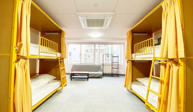 Two yellow bunk beds with privacy curtains at Sakura Hotel Jimbocho in Tokyo, Japan
