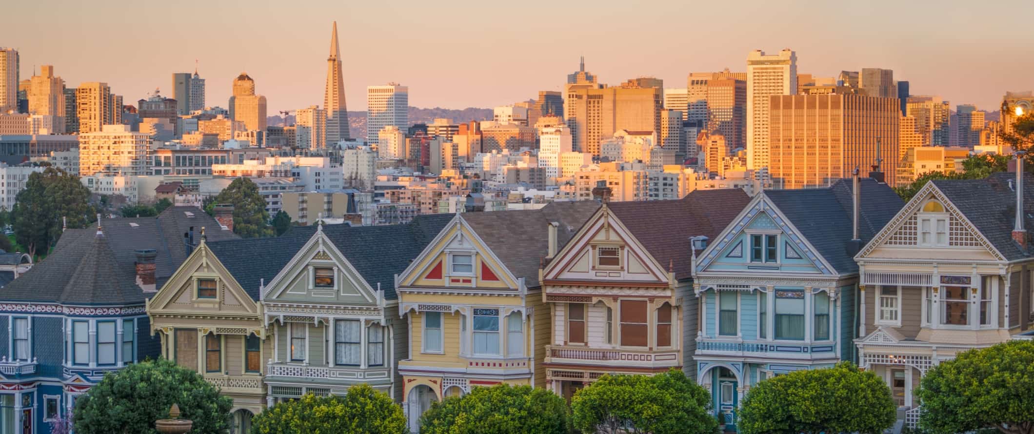 View of the Painted Ladies, iconic, pastel-colored Victorian houses with the downtown San Francisco skyline in the background in San Francisco, California.