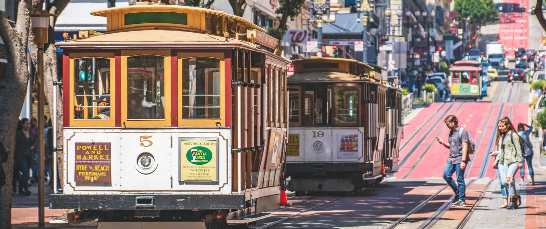 People boarding two historic trolleys in San Francisco, California.