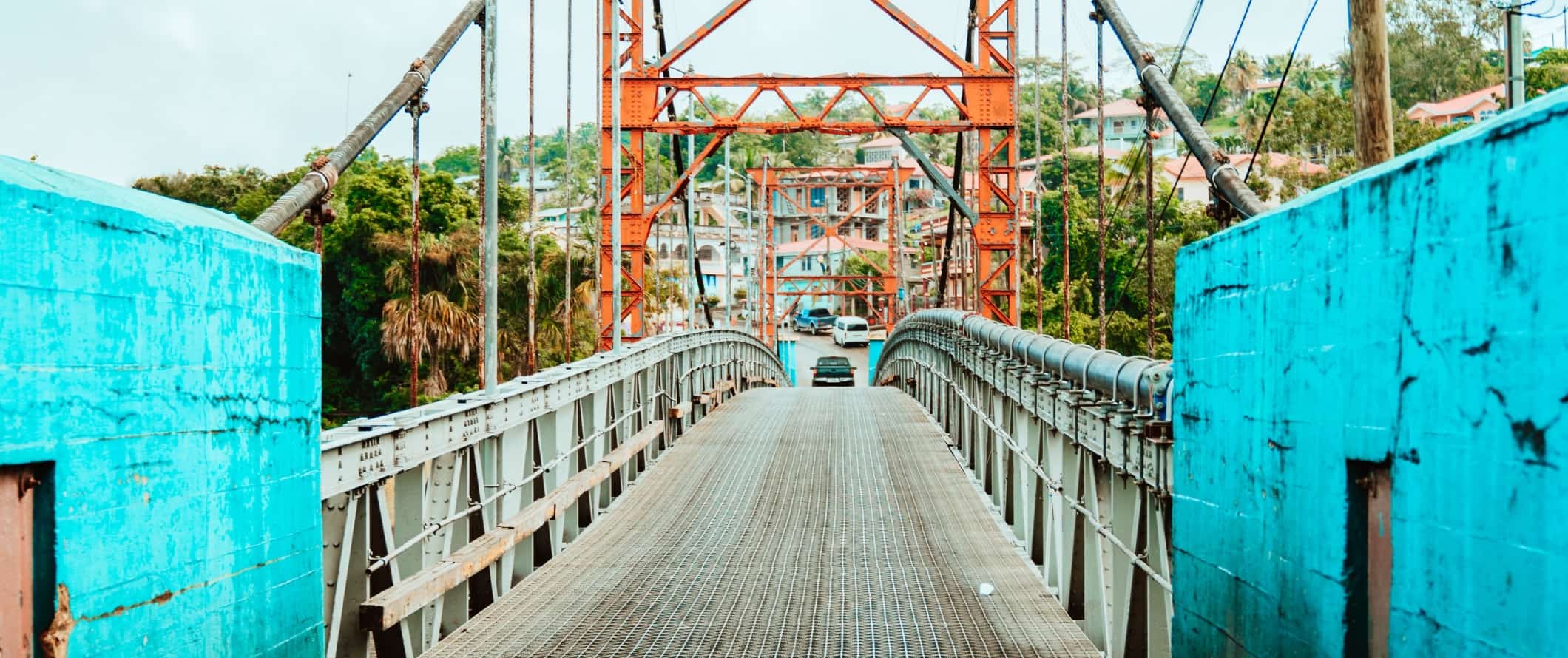 Metal bridge with bright blue walls and a car driving over it in San Ignacio, Belize