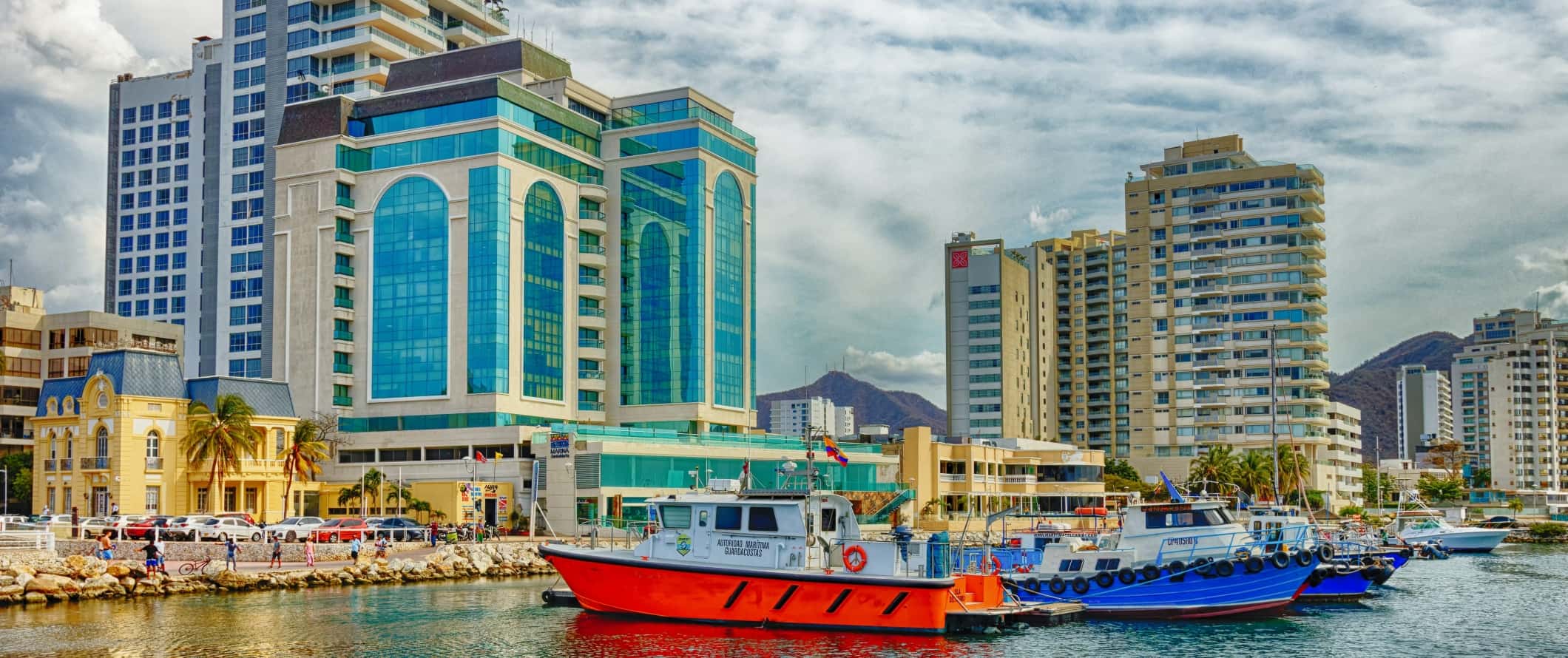 Colorful boats in the harbor with skyscrapers in the background in the city of Santa Marta, Colombia