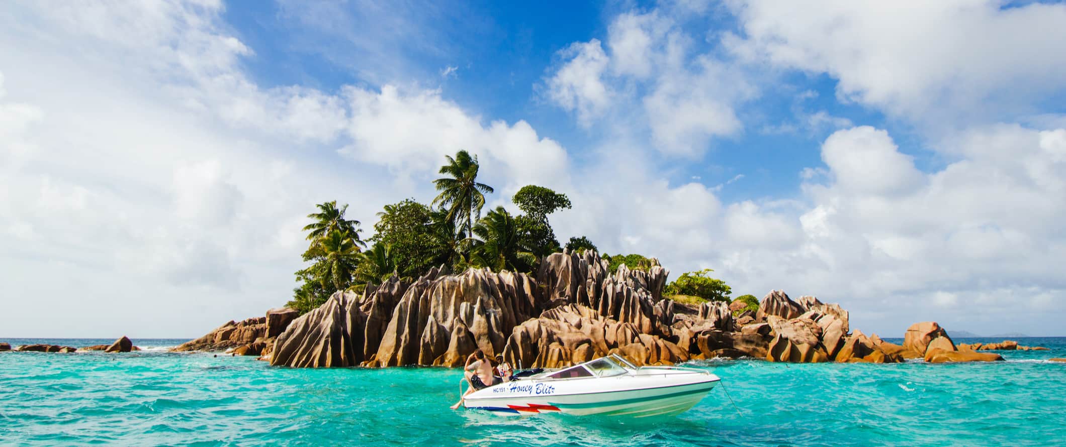 A boat anchored near a small island in the Seychelles during a beautiful sunny day