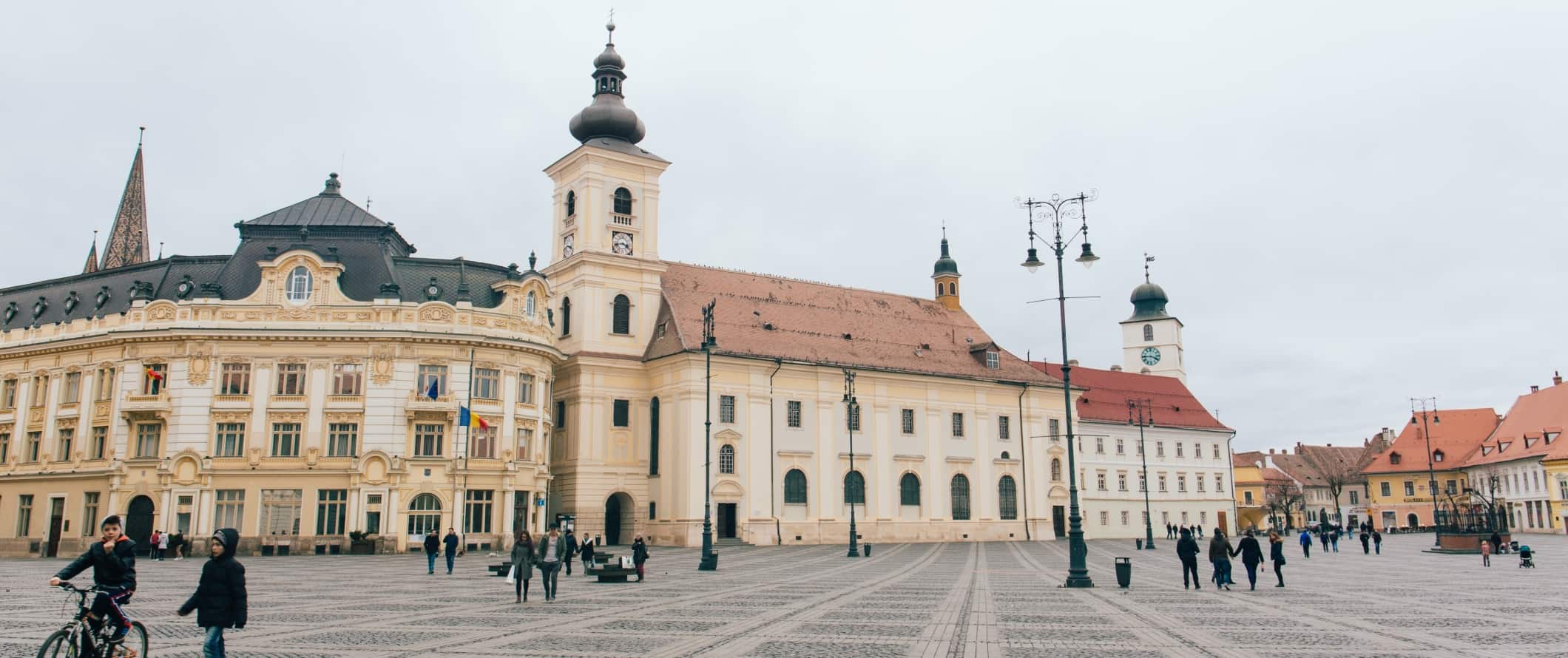 People walking through a square in the historic Old Town in Sibiu, Romania