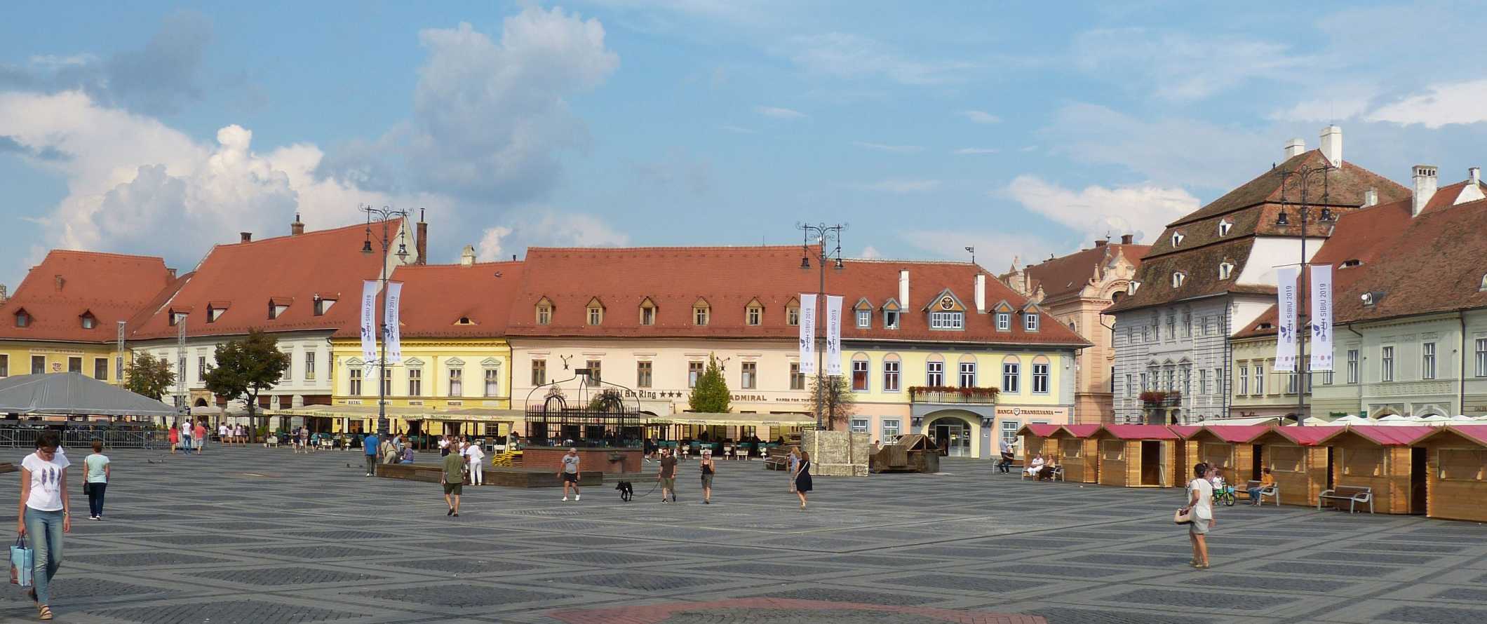 People walking through a Piata Huet, the main square in the historic Old Town in Sibiu, Romania