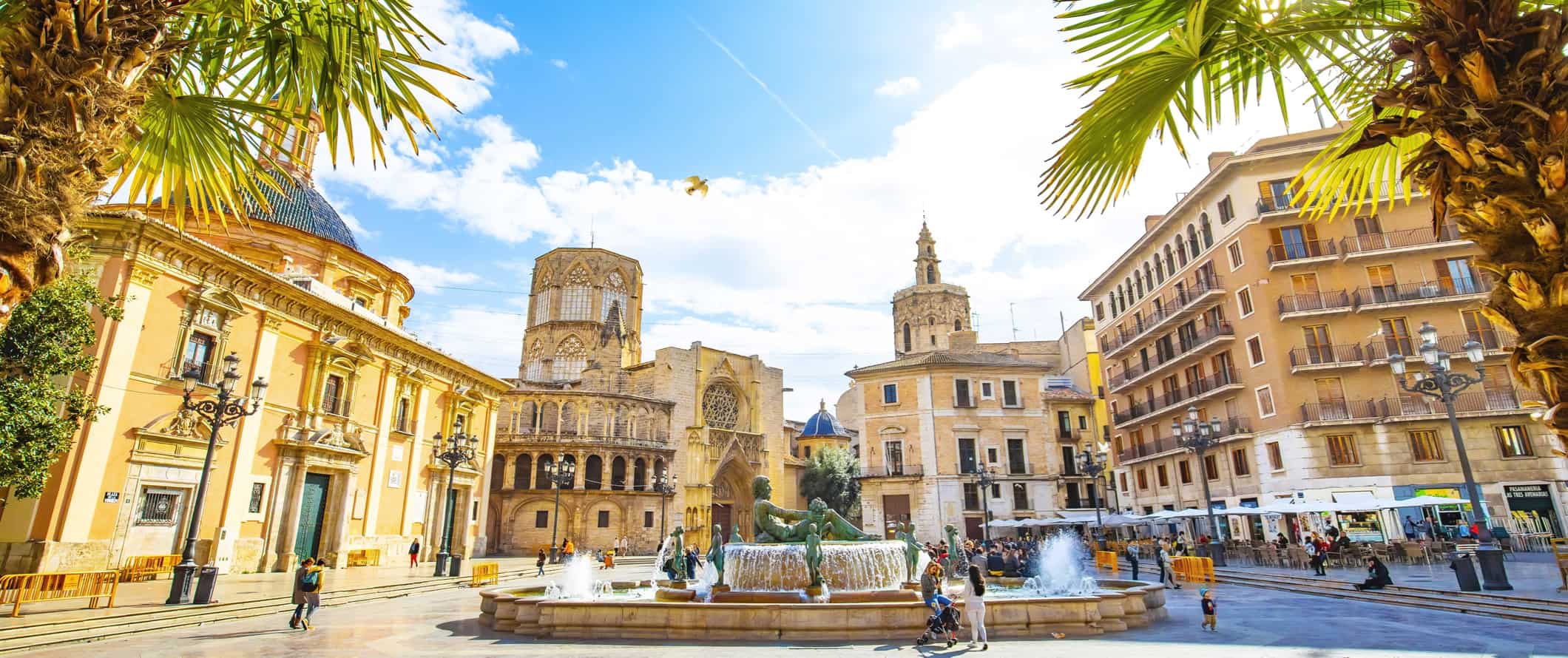 A relaxing street scene in sunny Valencia, Spain, featuring historic buildings and locals out for a stroll