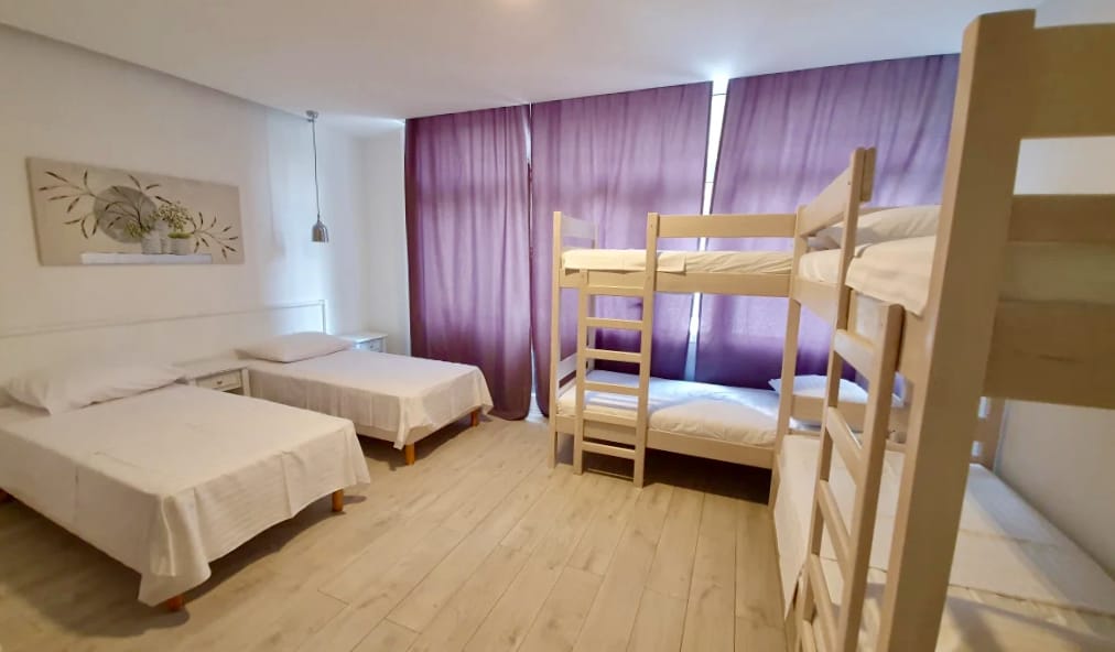 The interior of a large dorm room with two single beds and bunk beds in the Sweet Spot Hostel in Split, Croatia