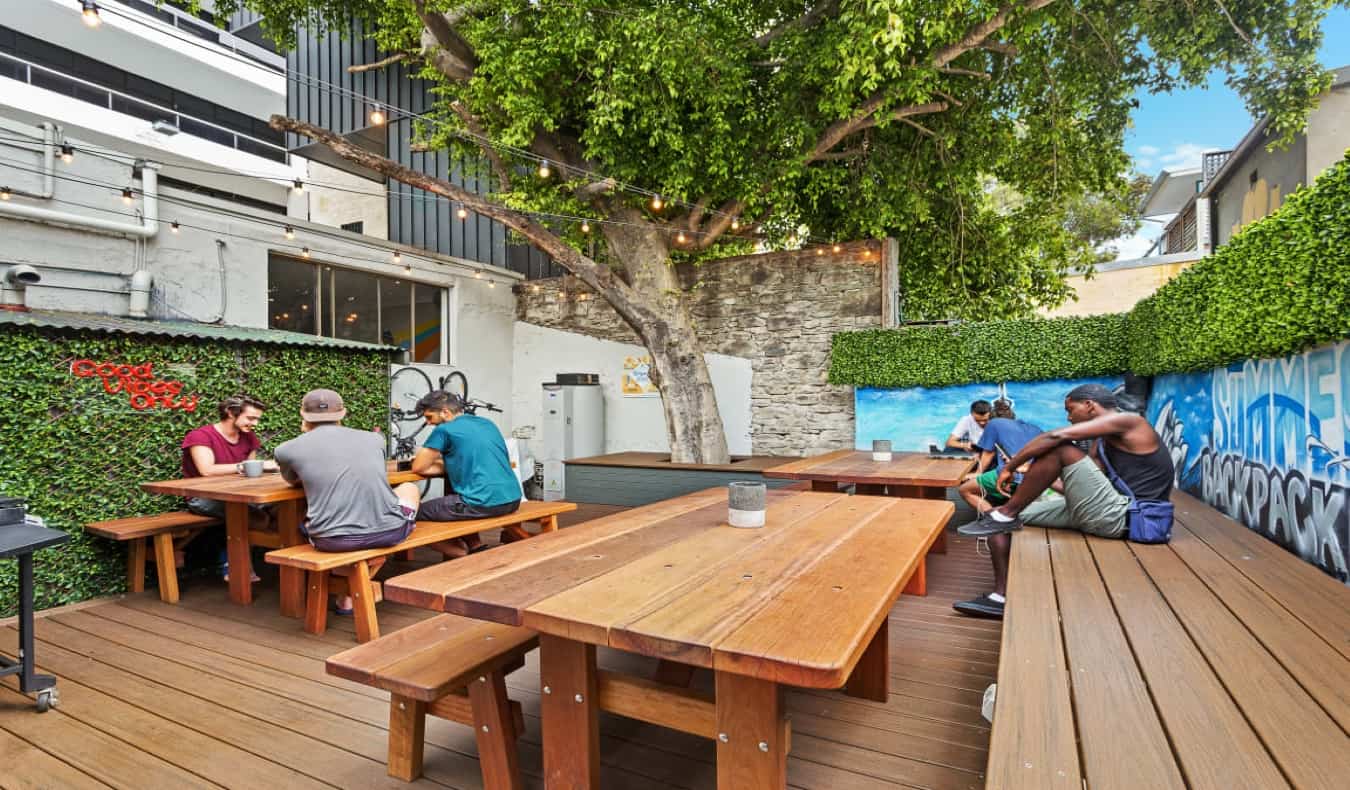 outdoor courtyard with wooden picnic tables and benches at Summer House Backpackers Hostel in Sydney