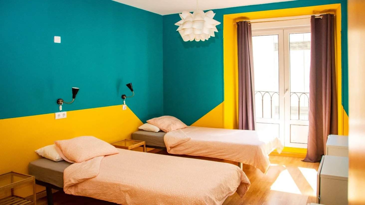 Two twin beds in a brightly painted room at Sungate One hostel in Madrid, Spain.