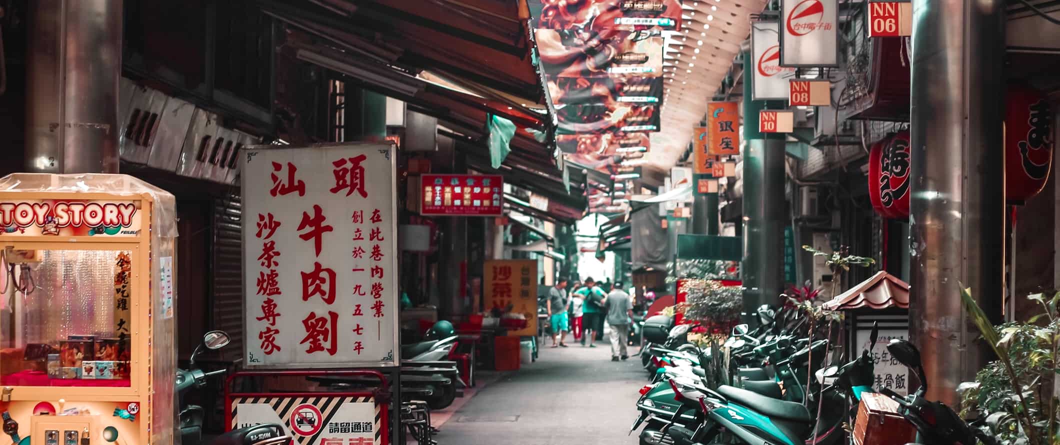 A narrow alley lined with scooters and shops in busy Taiwan