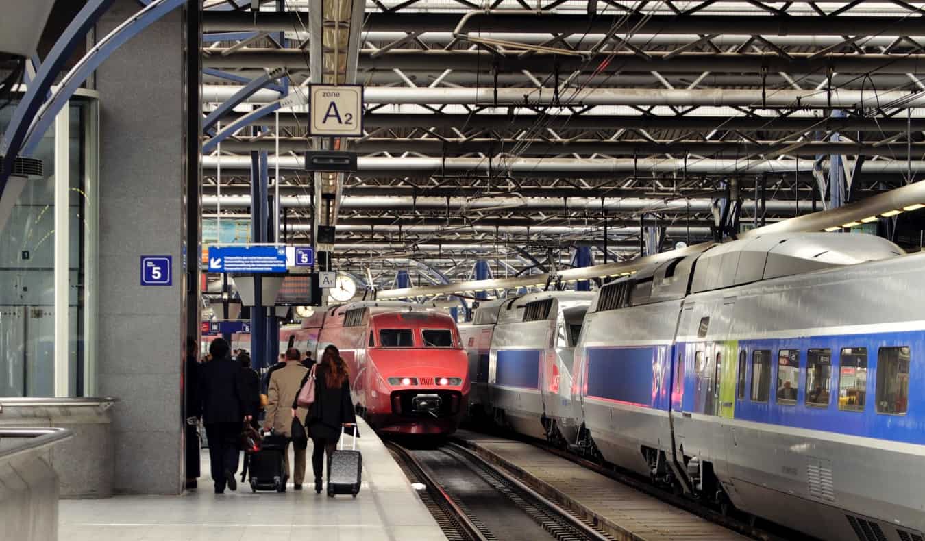 train station with people rolling luggage next to parked locomotives