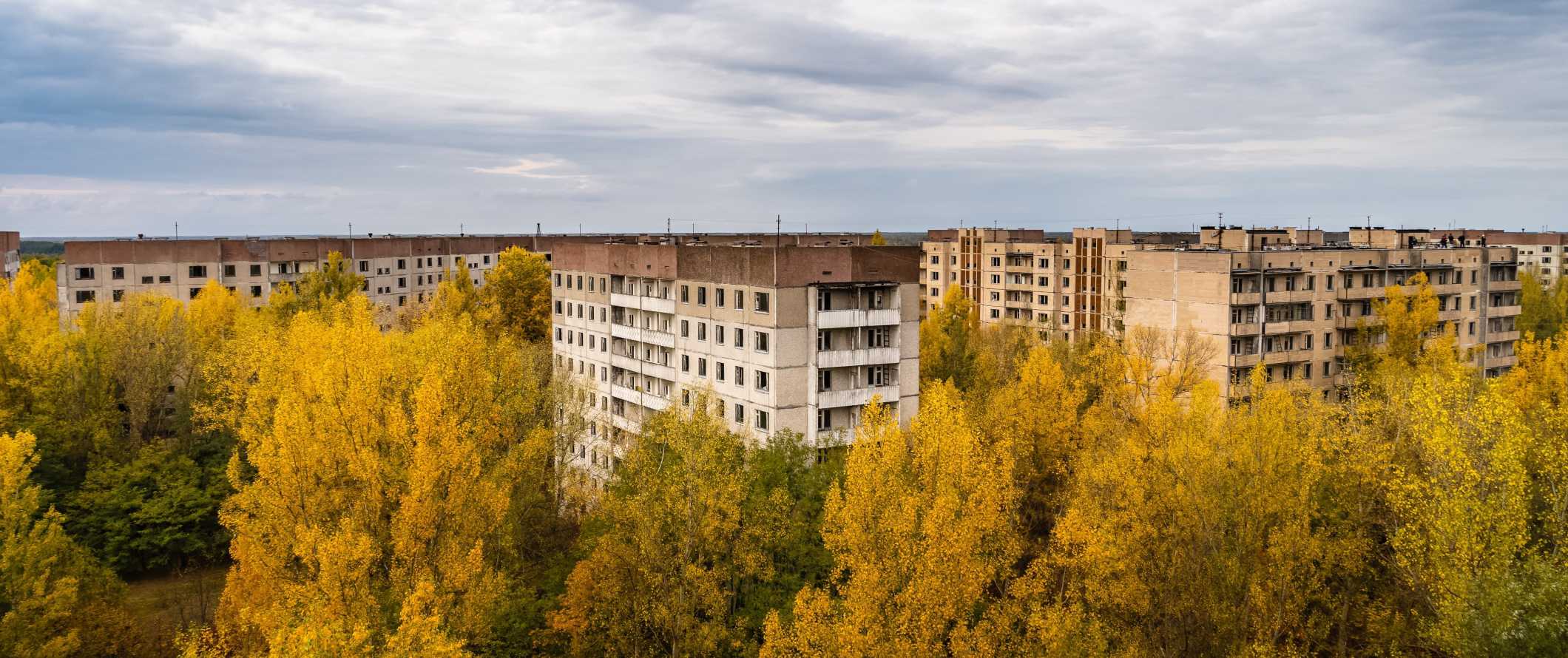 View over the abandoned apartment buildings with trees growing around them in Chernobyl, Ukraine