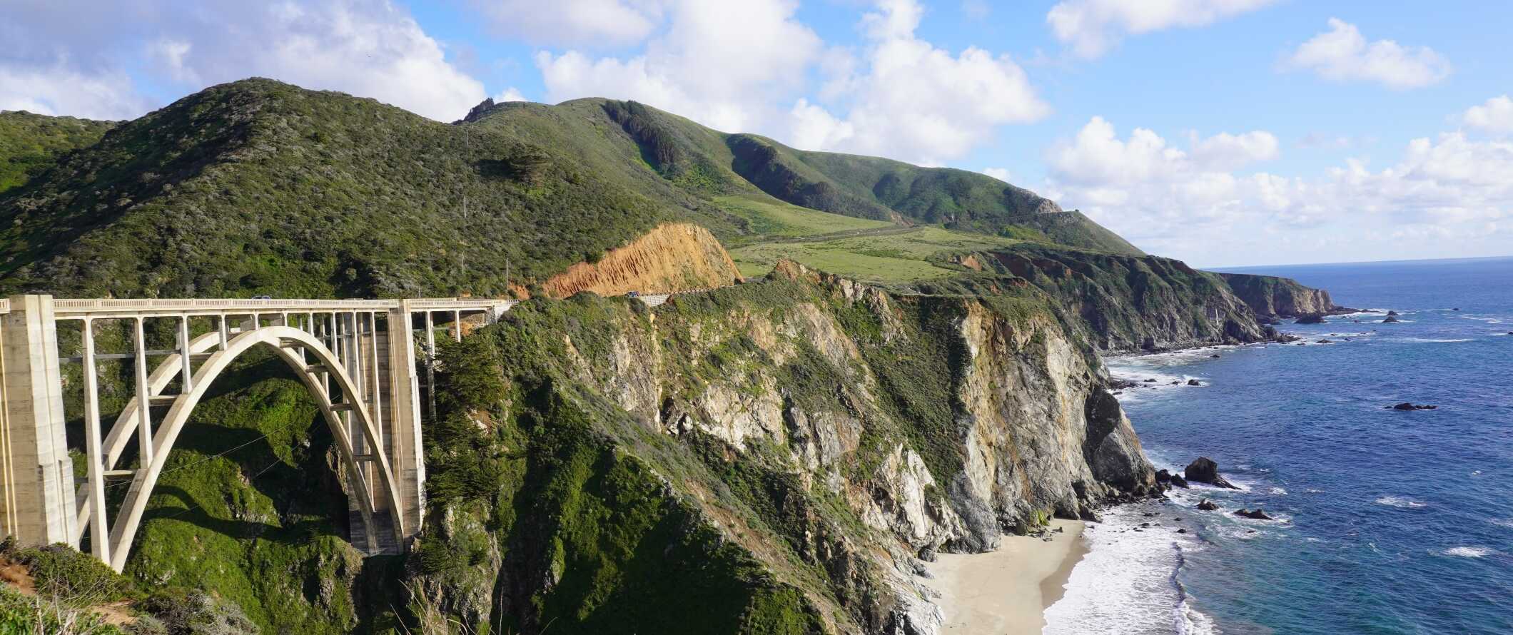 Arched Bixby Creek Bridge along the Pacific Coast Highway, with lush hills in the background, in California, United States.