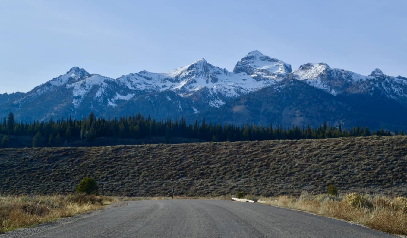 A lone road in Wyoming near Grand Teton National Park and its snow-capped mountains