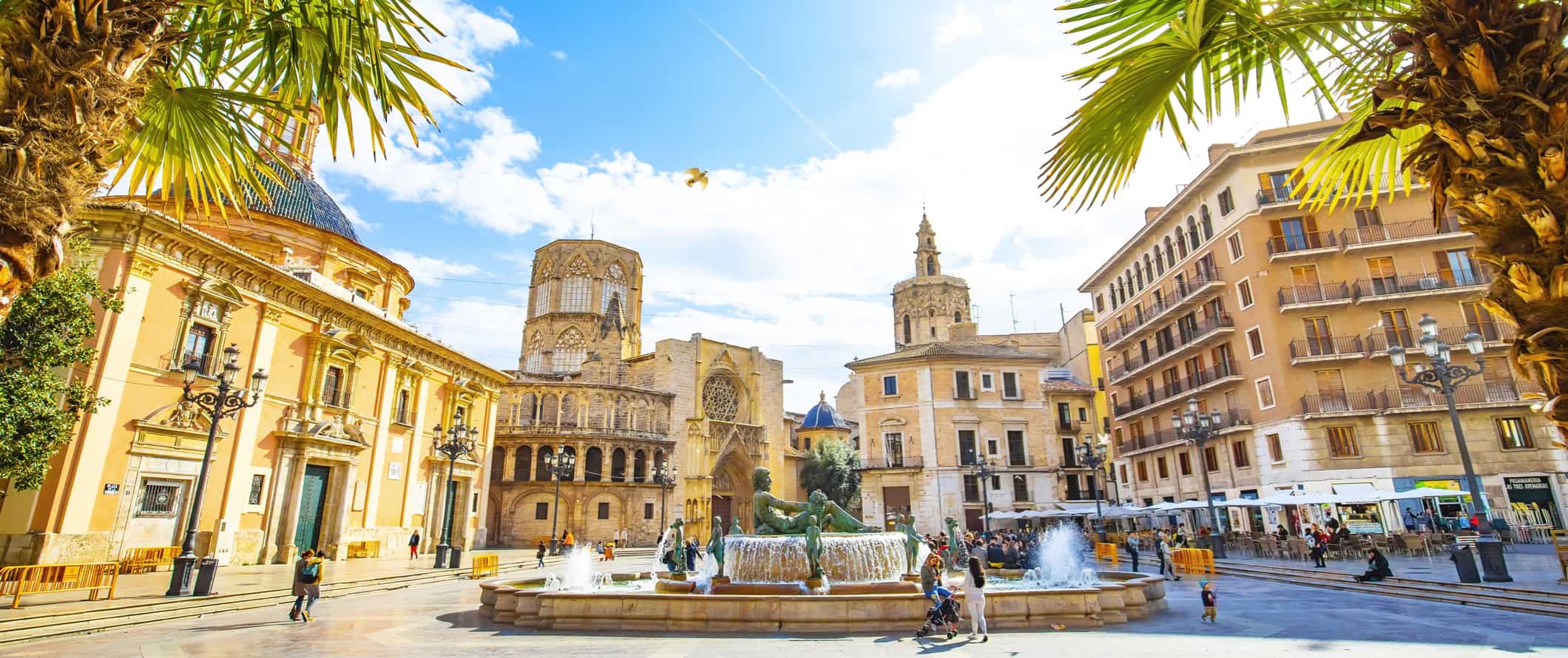 The stunning historic architecture of Valencia, Spain, featuring old buildings and a fountain surrounded by people