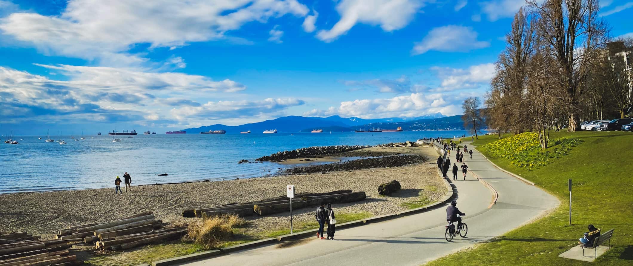 People walking and cycling along the coast of sunny Vancouver, Canada