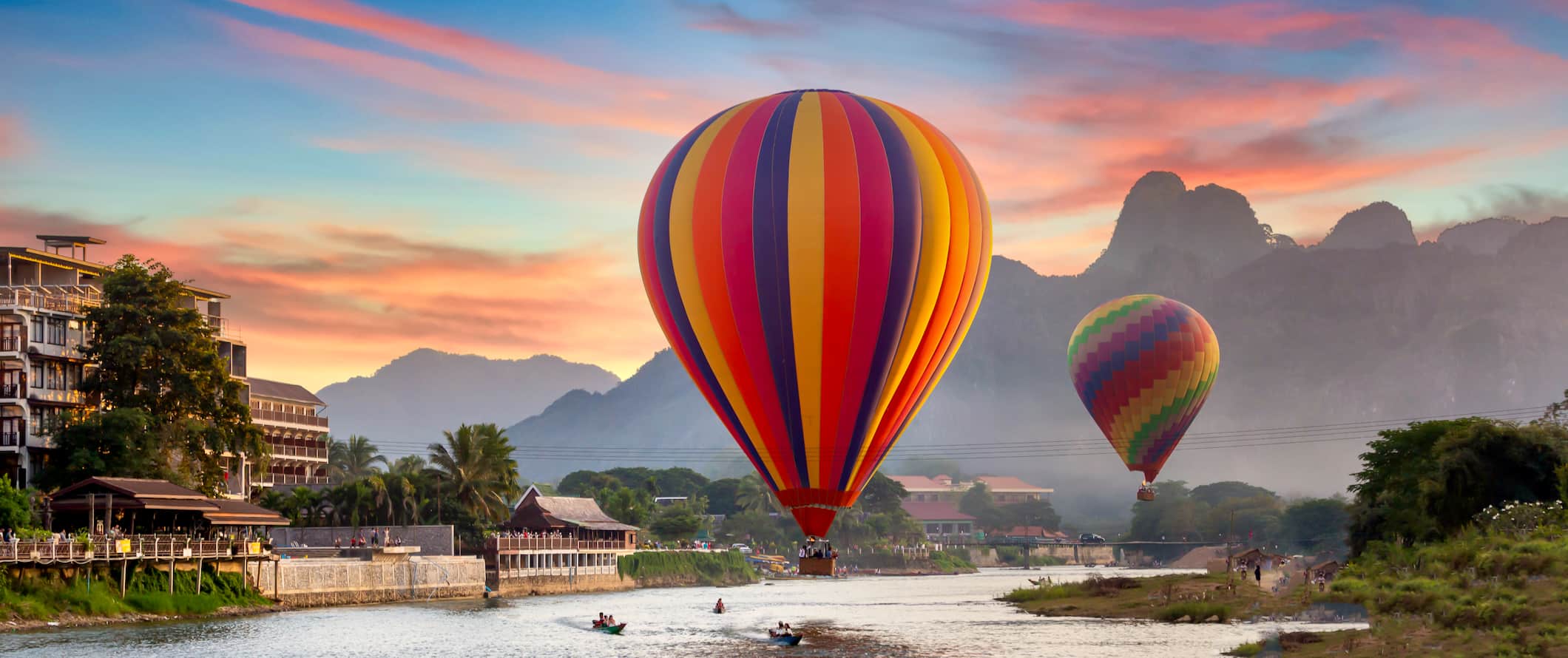 Hot air balloons flying over the water in rural Vang Vieng, Laos