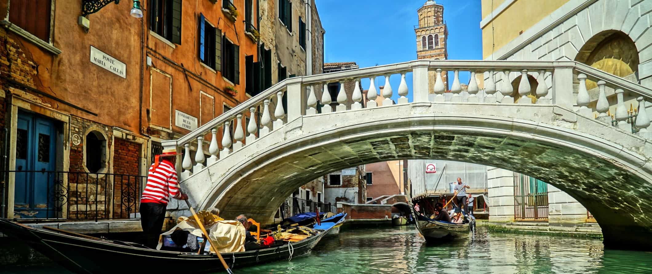 Man steering a gondola through a canal in Venice, Italy