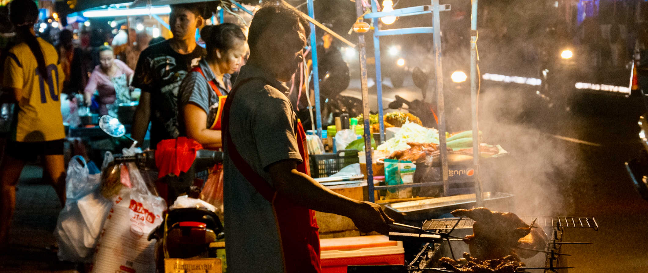 A local Laos street food vendor cooking during a night market in Vientiane, Laos
