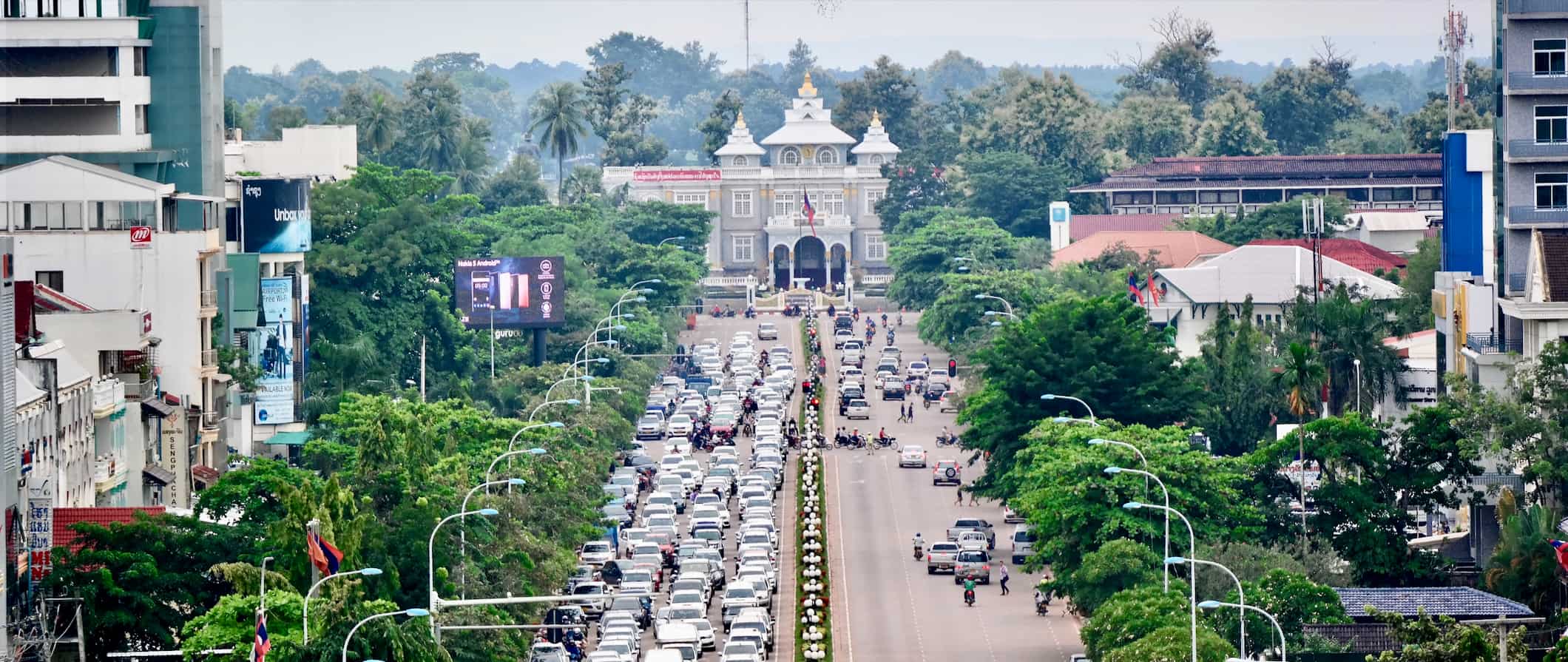 A busy, wide road full of traffic in Vientiane, the capital of Laos