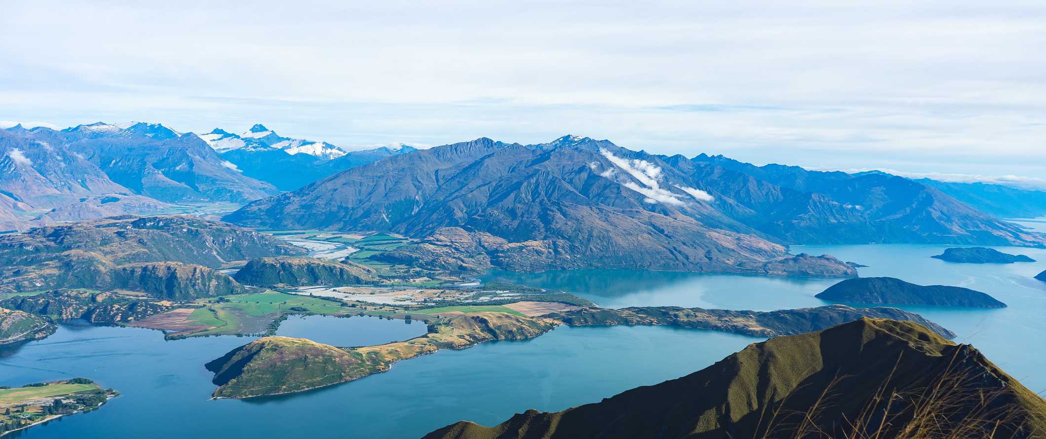 Roys Peak, a famous mountain in the foreground, with mountains and lakes behind it in Wanaka, New Zealand