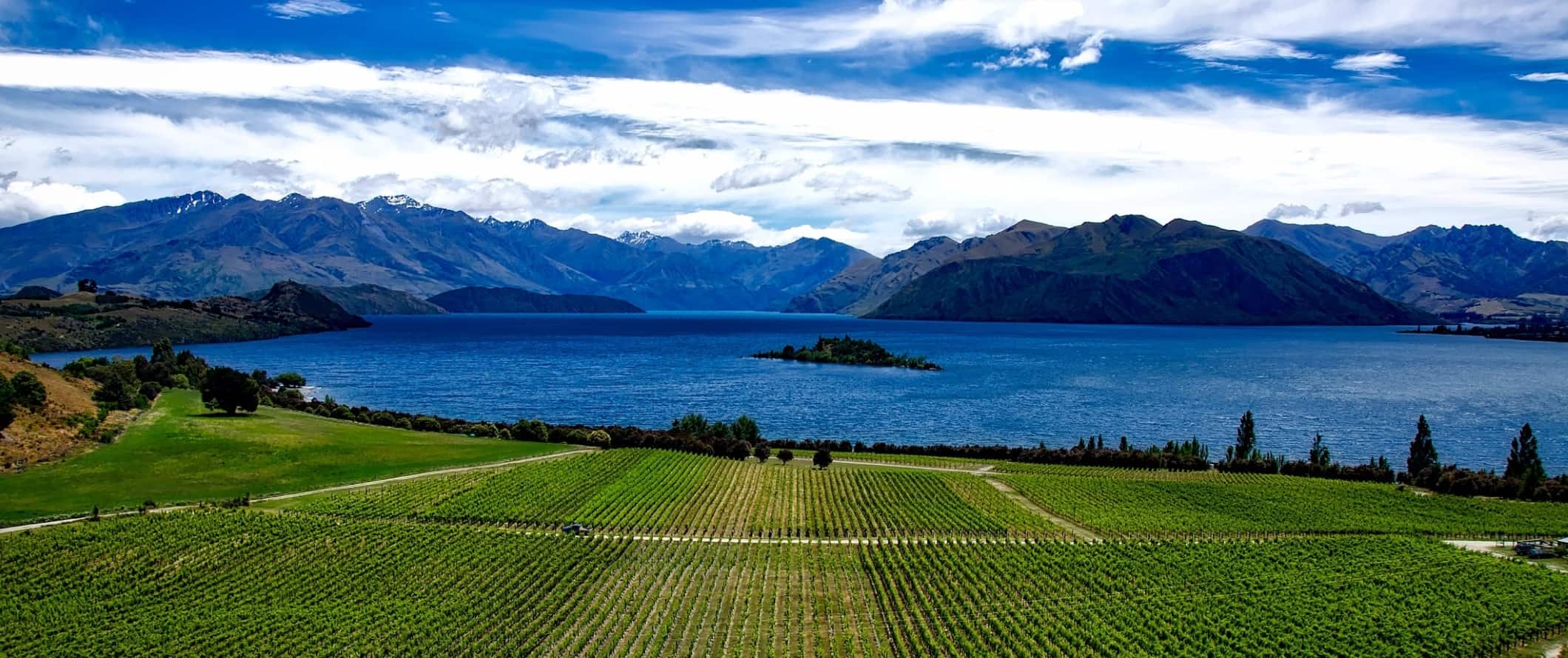 Roys Peak, a famous mountain in the foreground, with mountains and lakes behind it in Wanaka, New Zealand.