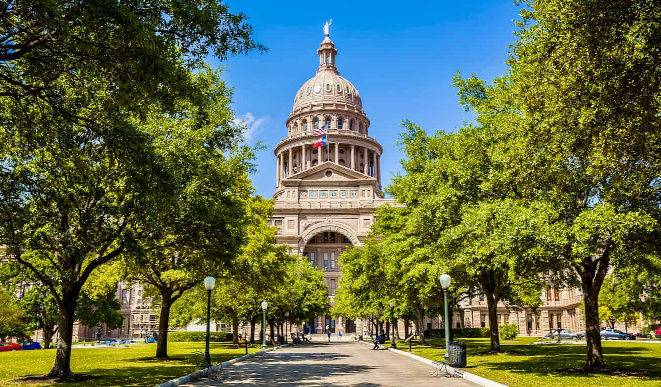 The State Capitol building surrounded by trees and greenery in Austin, Texas