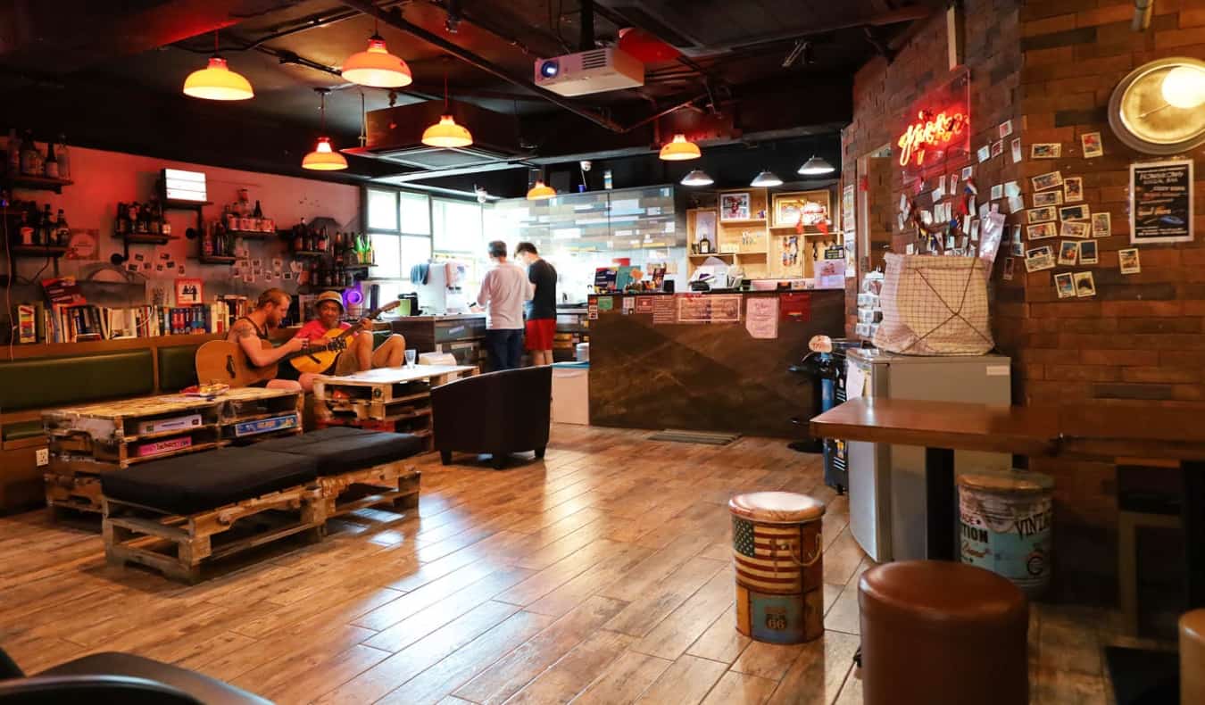 All wooden, cozy common room with people playing guitars at Yesinn Hostel in Hong Kong